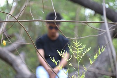 Midsection of man standing by tree in forest