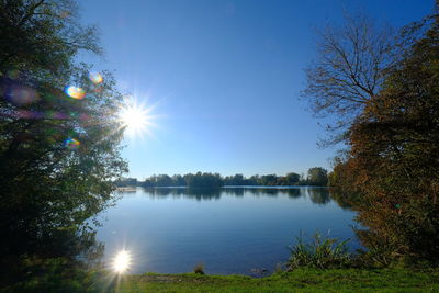 Scenic view of lake against blue sky on sunny day