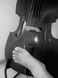 Close-up of hand playing guitar against gray background