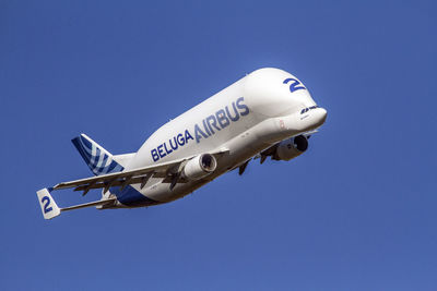 Low angle view of airplane against clear blue sky