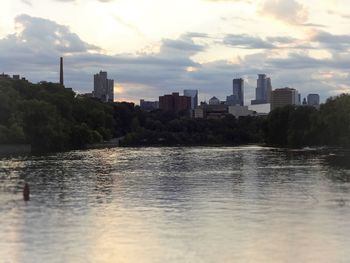 Scenic view of lake by city against sky during sunset