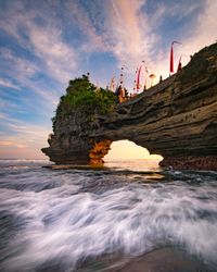 Rock formations by sea against sky during sunset