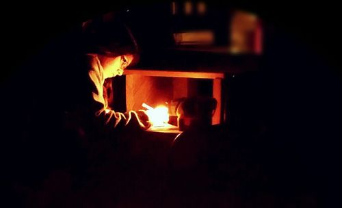 View of lit candle in dark room