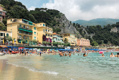 People on beach by buildings against sky