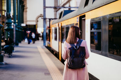 Woman walking by train on railroad station platform