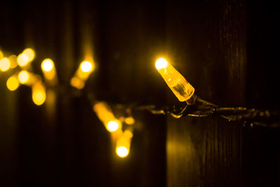 Close-up of illuminated light bulb hanging at night