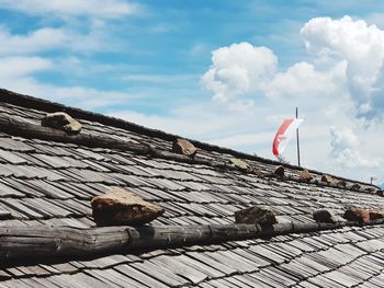 Low angle view of flags on roof against sky