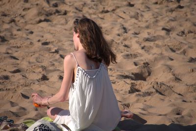 Rear view of woman sitting on beach