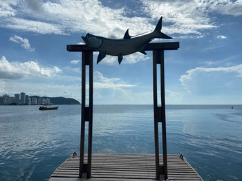 Lifeguard hut on sea against cloudy sky