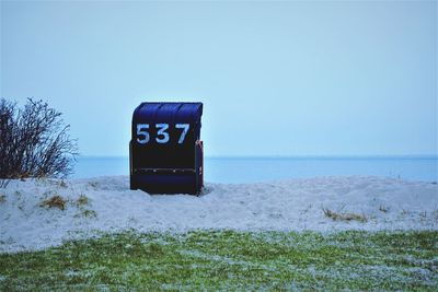 Information sign by sea against clear sky