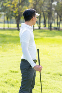 Side view of mid adult man standing at golf course