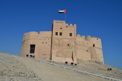 Low angle view of fort against clear blue sky