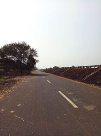 Road by trees against clear sky