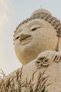 Low angle view of buddha statue against sky