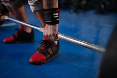 Cropped sportsman lifting barbell in gym