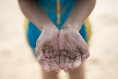 Midsection of woman with sand on hands