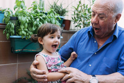 Grandfather and granddaughter singing together on the terrace