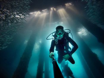 Portrait of young man with monopod while scuba diving in sea