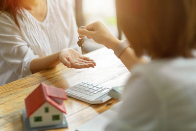 Midsection of woman holding paper while sitting on table