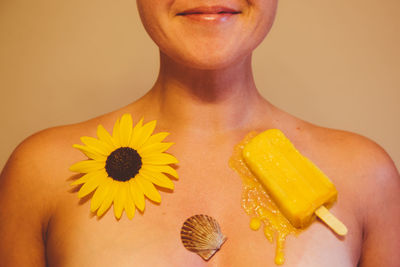 Sunflower and yellow flavored ice with seashell on naked woman