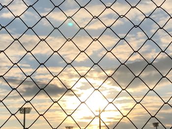 Full frame shot of chainlink fence against sky during sunset