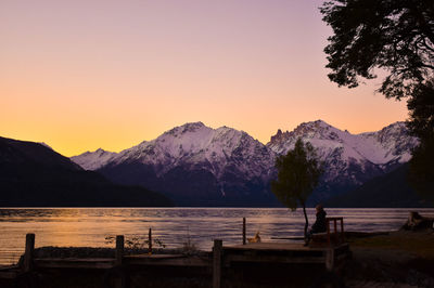 Snowcapped mountains by lake during sunset