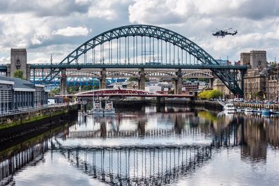 Bridge over river in city against sky