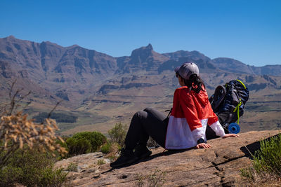 Rear view of woman on mountain against sky looking at mountain peak ahead