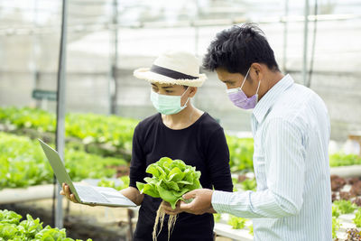 Young man holding woman standing against plants