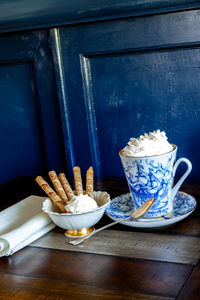 Gourmet hot chocolate and whip cream in a nautical china mug with cookies on a rustic table 