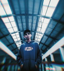 Portrait of young man standing against ceiling