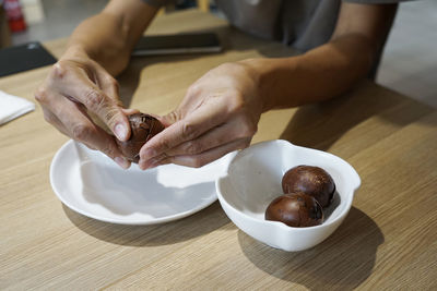 Man's hand peeling a tea infused egg at a tea house in kuala lumpur, malaysia