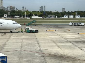 Airplane on airport runway against sky in city