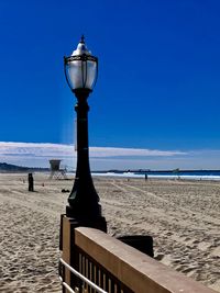 Street light on beach against clear blue sky
