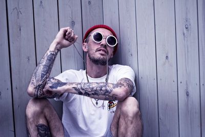 Man leaning against wooden wall