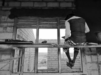 Rear view of young man sitting on plank at construction site