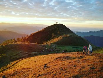 People on mountain against sky during sunset