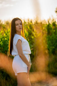 Portrait of young woman standing against trees