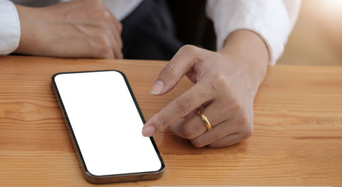 Midsection of man using smart phone on table