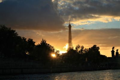 Silhouette of trees at riverbank during sunset