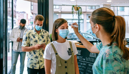 Woman checking temperature of customers