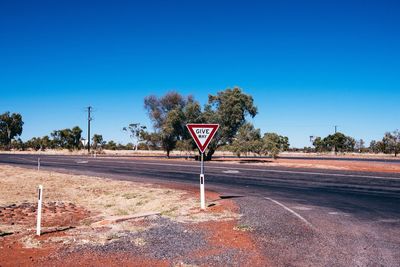 Road sign against clear blue sky