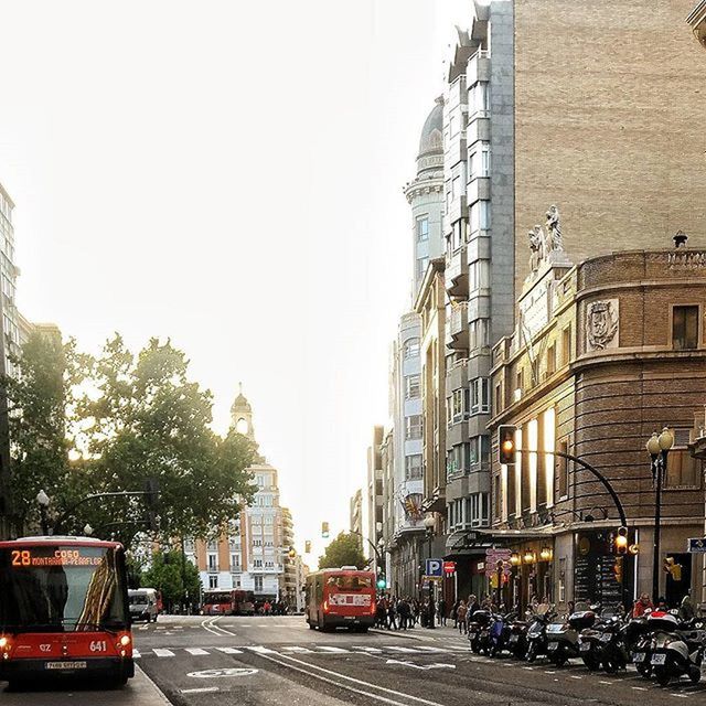 transportation, building exterior, car, architecture, land vehicle, built structure, mode of transport, street, city, road, clear sky, city street, tree, traffic, city life, the way forward, incidental people, building, day, vehicle