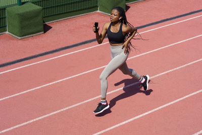 African woman athlete running on racetrack. sportive black female training jog on stadium sprinting