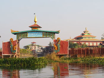 Traditional building by lake against sky