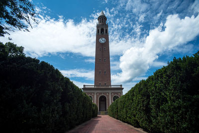 Footpath leading towards clock tower against sky