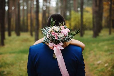 Portrait of woman with pink flower against trees in forest