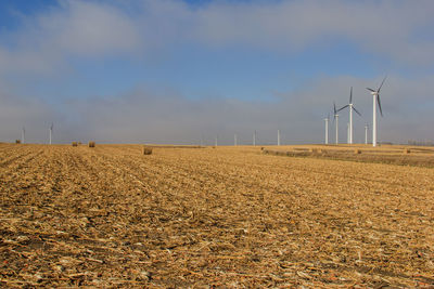 Wind turbines in field against sky