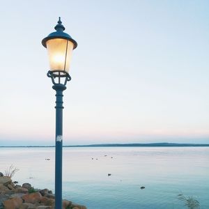 Street light by sea against clear sky