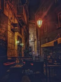 Illuminated restaurant by buildings in city at night